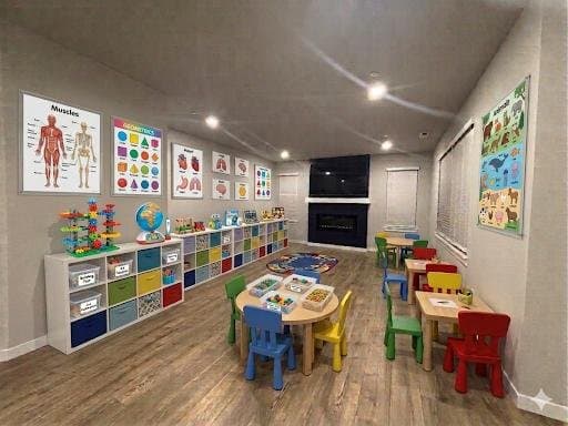 A classroom with anatomy and shape charts, toy shelves, and child-sized tables and chairs